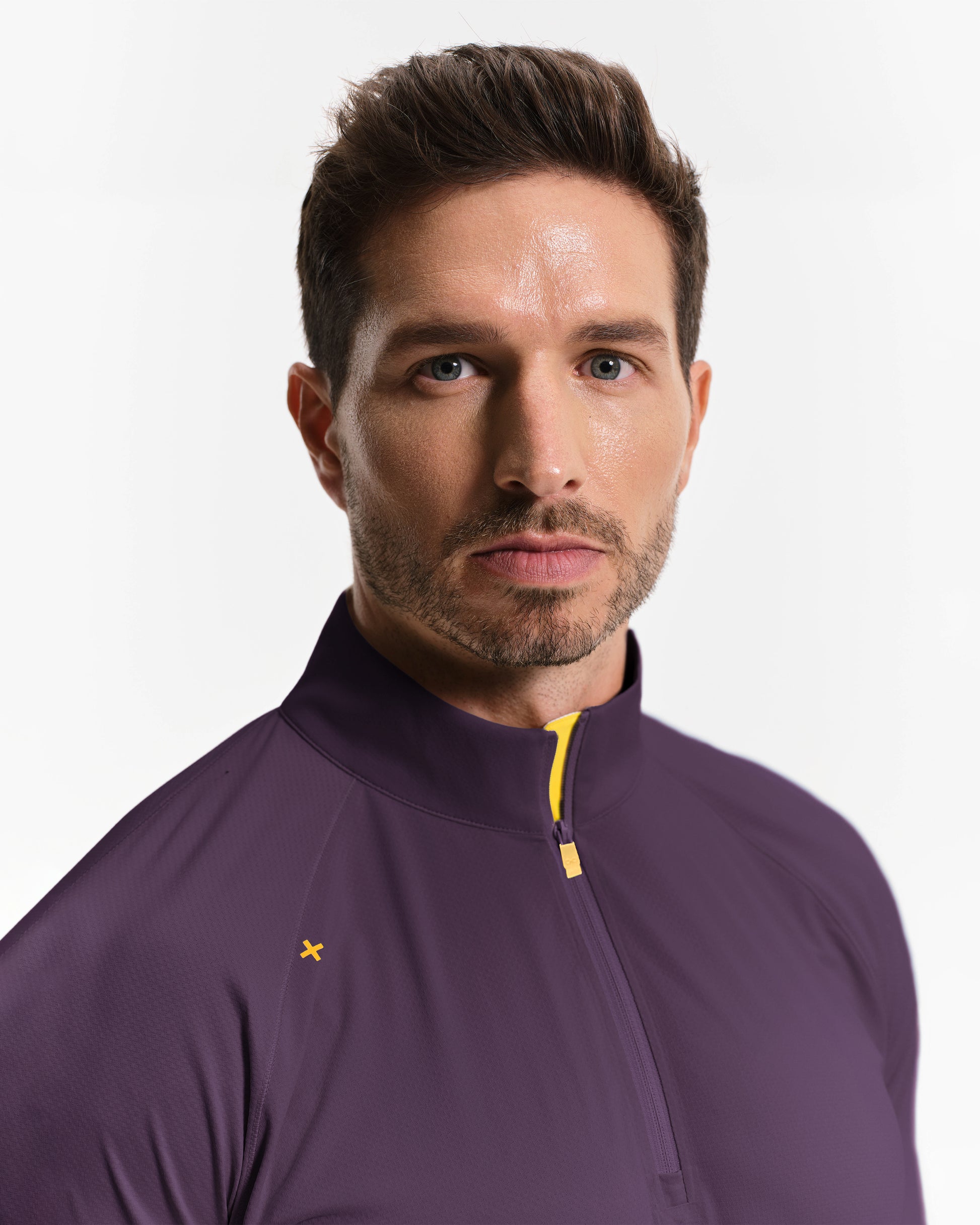 Man wearing a purple jacket with a yellow zipper on a gray background